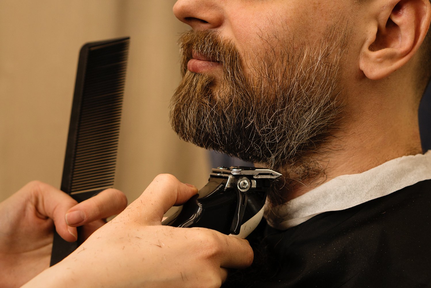 Barber Trimming Man's Beard with Electric Razor